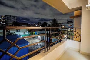 A balcony with a view of a cityscape at night, featuring buildings and a cloudy sky. - Opal Suite Rooms (Pune)
