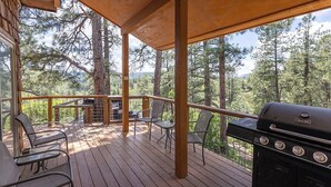 A covered deck with a grill and chairs, overlooking a forested area. - Hot Tub, Secluded, Borders National Forest, New AC (Pagosa Springs)