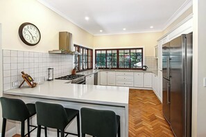 Kitchen features a central island with a gas stove and oven, white cabinetry, and a stainless steel refrigerator.