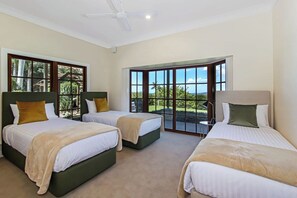 Three single beds, a balcony with a view, and a ceiling fan for comfort.