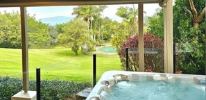Relax in a serene hot tub surrounded by lush greenery and a tranquil pool.