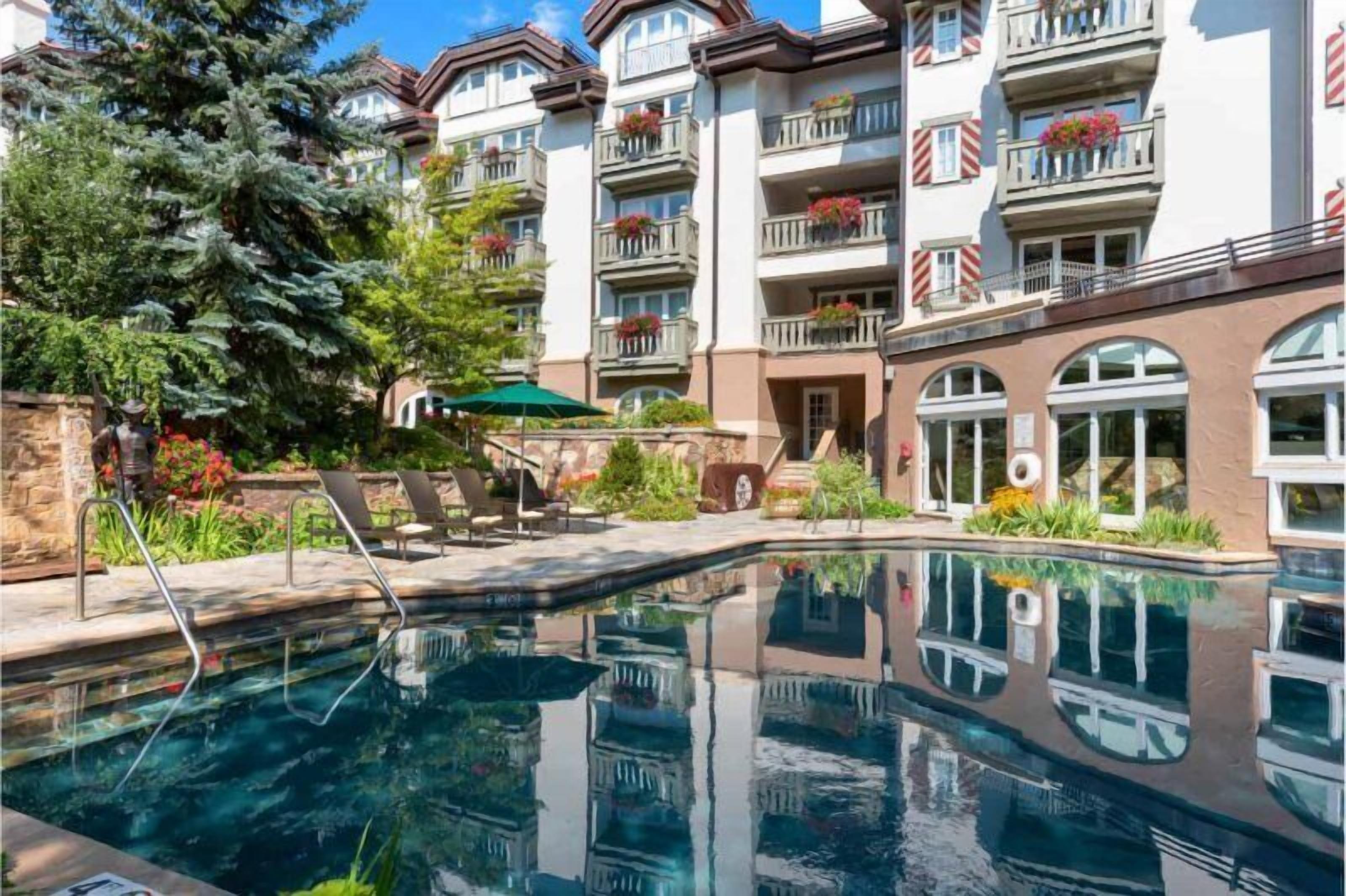 Un hôtel doté d’une piscine, d’un espace extérieur aménagé et de balcons ornés de jardinières.