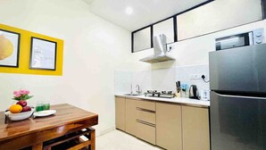 A compact kitchen with a wooden table, a sink, a stove, and a refrigerator.