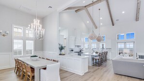 A spacious kitchen with a large island, white cabinetry, and a chandelier.