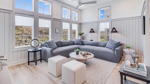 A spacious living room with a large gray sectional sofa, a round coffee table, and a ceiling fan.