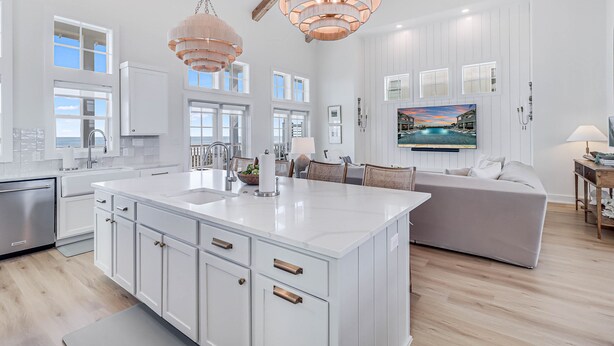 A spacious kitchen with a large island, white cabinetry, and pendant lighting.