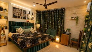 A bedroom with a bed, bedside tables, a chair, a standing lamp, a ceiling fan, and decorative wall art. - Dhairya Villa Home Away From Home (Jammu)