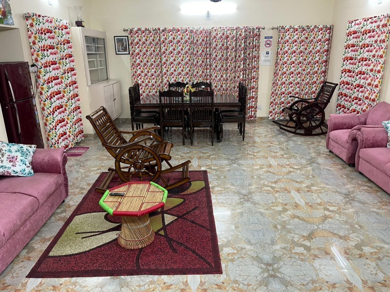 A living room with a dining table, chairs, a sofa, and a patterned rug.