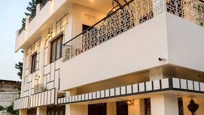 A two-story building with a balcony, a ceiling fan, and potted plants. - Dhairya Villa Home Away From Home (Jammu)