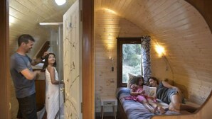 Interior acogedor de una cabaña con paredes de madera, una cama con almohadas y una mesita.
