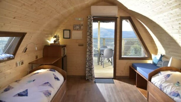 Una cabaña acogedora de madera con dos camas, un escritorio y un balcón con vistas.