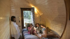 Interior acogedor de una cabaña con cama, ventana con cortinas y vistas al exterior.