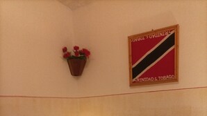 Een slaapkamer met een bed, kussens, een nachtkastje met een kaars, een bloempot aan de muur en een vlag.