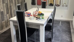 Un espace repas avec une table blanche, des chaises noires et un luminaire suspendu au design moderne.