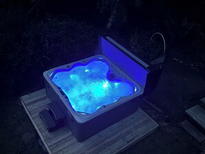 Una vasca idromassaggio illuminata da una luce blu, posizionata su un pontile di legno.