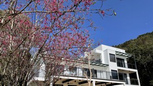 A modern two-story building with a balcony and a covered patio area. - Dear house (Puli)