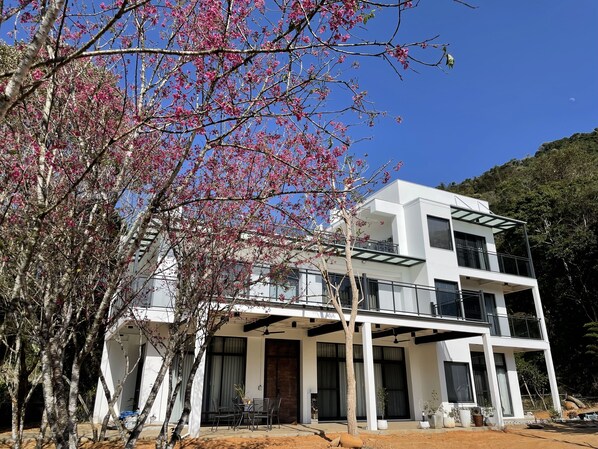 A modern two-story building with a balcony and a covered patio area.