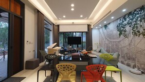 A modern living room with a large TV, a piano, and a sofa. - Dear house (Puli)