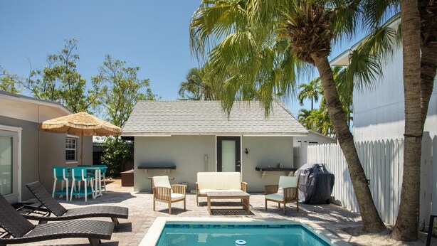 A backyard with a swimming pool, lounge chairs, a table, and a covered grill area. - Tranquil Retreat by the Beach-4 bedroom 3 bath home w/private pool, parking (Key West)
