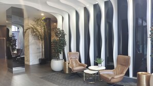 Un vestíbulo moderno con sillones de cuero, una pequeña mesa redonda y una planta grande en maceta.