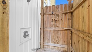 A wooden gate leading to a white door with a metal handle and a lock. - Lemoncello | Spacious for a Group, Elevator Access + Partial Ocean Views (Carolina Beach)