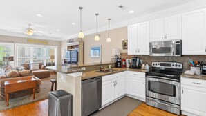 A modern kitchen with white cabinets, stainless steel appliances, and a central island. - Lemoncello | Spacious for a Group, Elevator Access + Partial Ocean Views (Carolina Beach)