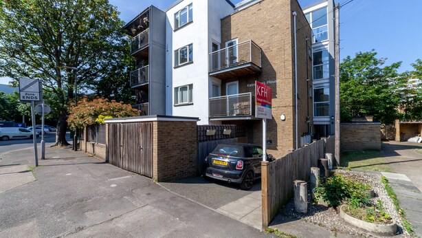 A modern two-story building with a brick facade, a balcony on the upper floor, and a 'For Sale' sign. - The South Wimbledon Collection (London)