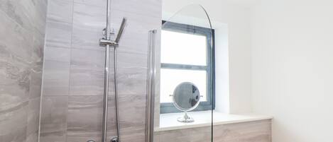 Een moderne badkamer met een douche, een wastafel en een raam.