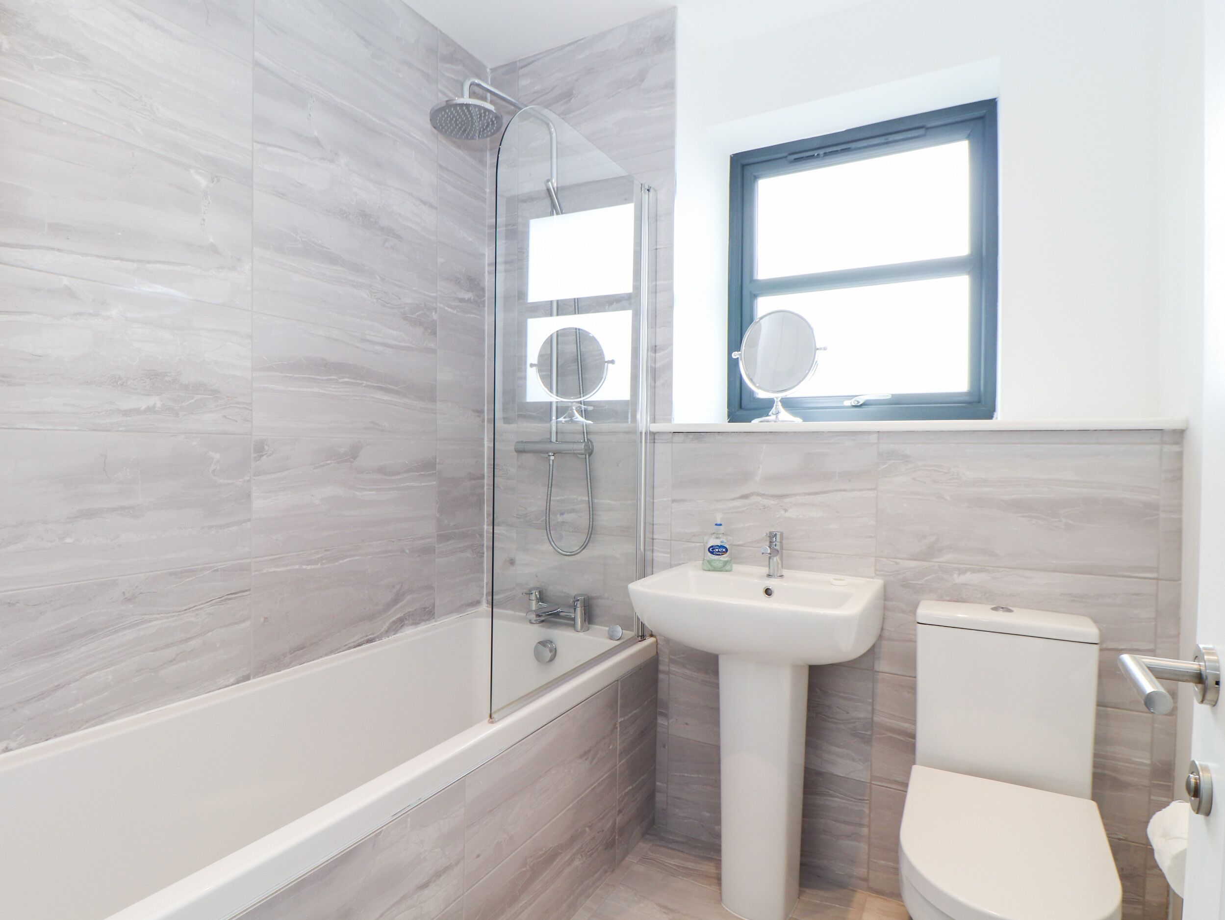 Une salle de bain moderne avec une douche à parois de verre, un lavabo sur colonne et des toilettes.