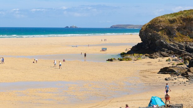 A wide sandy beach with a rocky outcrop on the right, a clear blue sky, and calm sea. - 1 Queensway Gardens (Hayle)