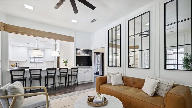 A modern living room with a brown sofa, white armchairs, and a coffee table. There is a kitchen in the background with white cabinets and a dining area with chairs. - Allen Abode - 4 Bedrm. Pool, Fire Pit , Charm (Allen)