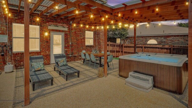 Eine überdachte Terrasse mit Whirlpool, Sitzgruppe und Lichterkette.