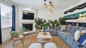 Ein modernes Wohnzimmer mit einer Couch, zwei Korbstühlen, einem Couchtisch und einem Kamin.