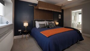 A bedroom with a large bed, two bedside tables with lamps, a window with a view, and a door leading to a bathroom.