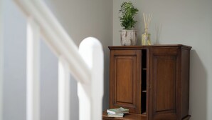 A wooden cabinet with a plant and reed diffuser on top.