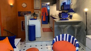 A compact living space with a kitchenette, a dining area with a chair, and a small kitchen counter.