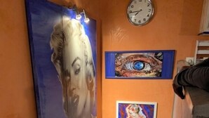 A staircase with a handrail, a clock on the wall, and three framed artworks.