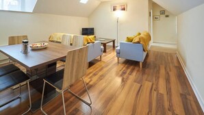 A modern living room with a wooden dining table, two sofas, and a TV. - Host & Stay | Scotsgate House (Berwick-upon-Tweed)