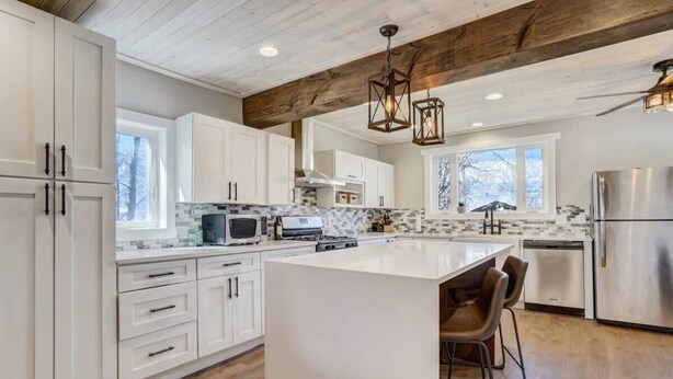 A modern kitchen with white cabinetry, a large island, and stainless steel appliances. - Hot Tub and Firepit Gazebo Pikes Peak Sunset Views (Colorado Springs)