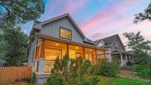 A two-story house with a covered porch, a fenced yard, and a well-maintained garden. - Hot Tub and Firepit Gazebo Pikes Peak Sunset Views (Colorado Springs)