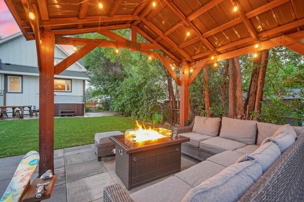 An outdoor patio with a fire feature, seating, and string lights.