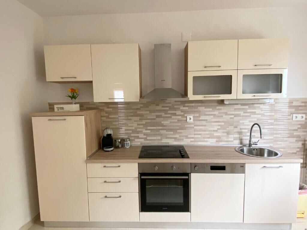 Una cuina moderna amb armaris de tons clars, forn integrat, rentaplats i microones.