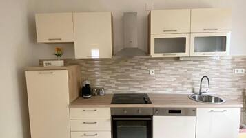 Una cuina moderna amb armaris de tons clars, forn integrat, rentaplats i microones.