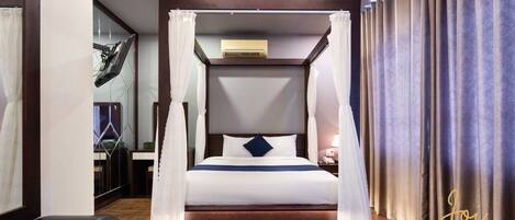Una habitación de hotel moderna con cama con dosel, una mesita de noche y un amplio ventanal con cortinas.