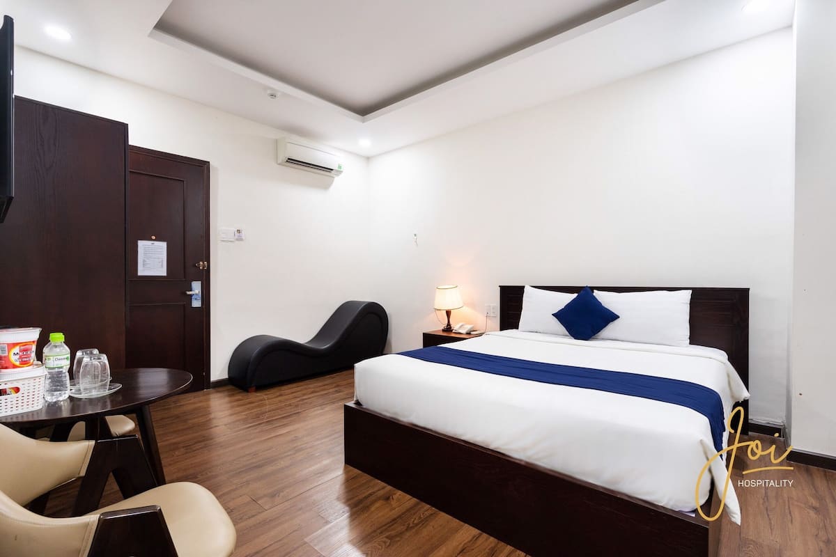 Habitació d'hotel amb un llit, escriptori, cadira i taula amb productes de benvinguda.