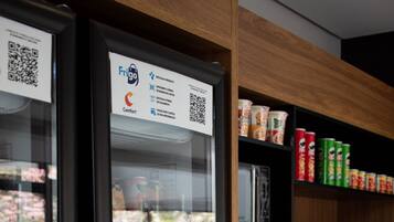 A vending machine with a QR code and a shelf stocked with various food items.