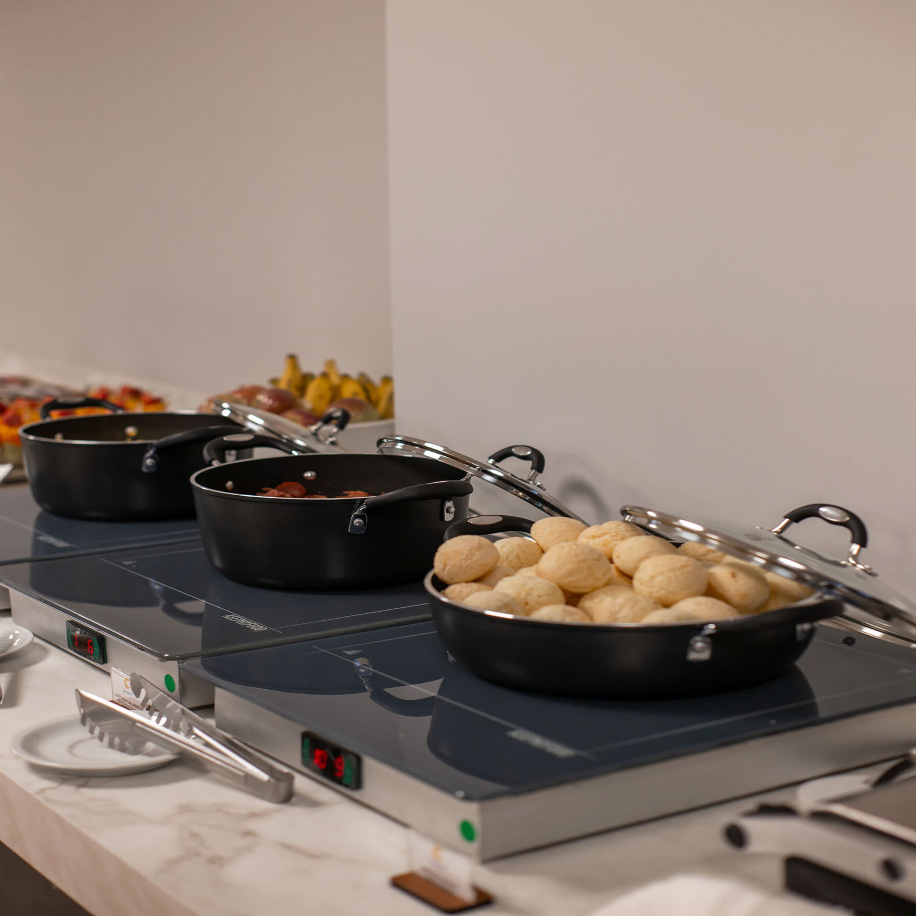 A buffet setup with various food items and cooking equipment.