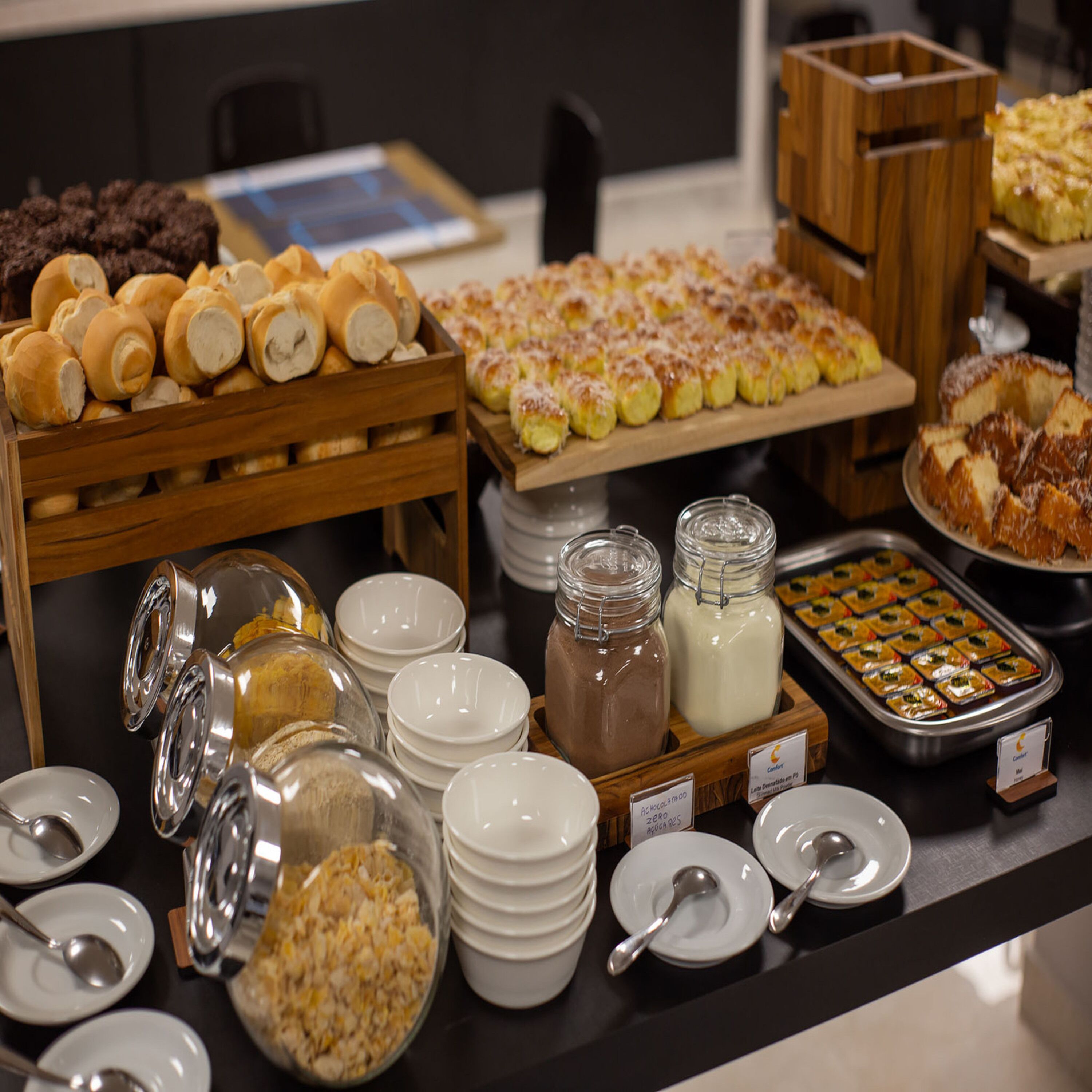 Buffet com diversos alimentos, incluindo pastelaria, pão e sobremesas.
