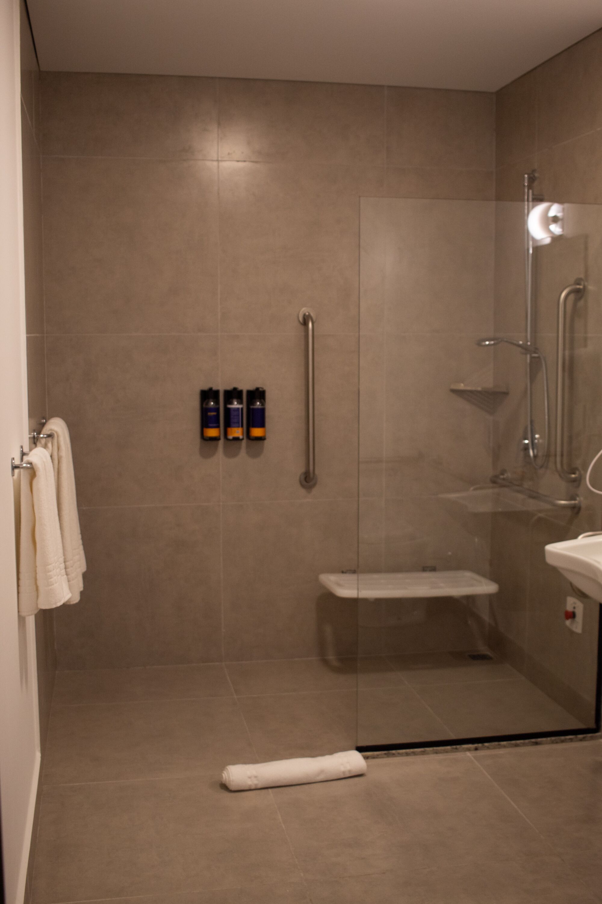 A modern bathroom with a glass-enclosed shower, a white sink, and a towel rack.
