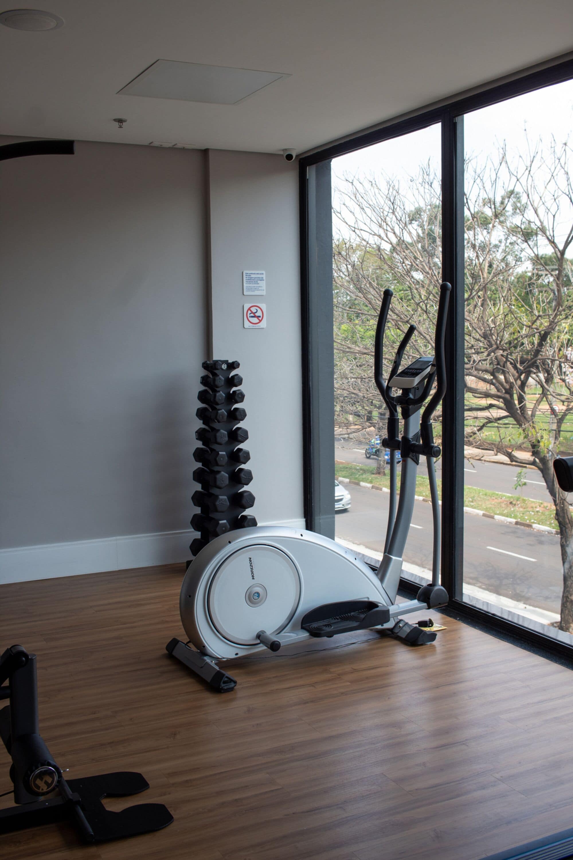 A gym with exercise equipment, a standing bike, and a wall-mounted dumbbell rack.